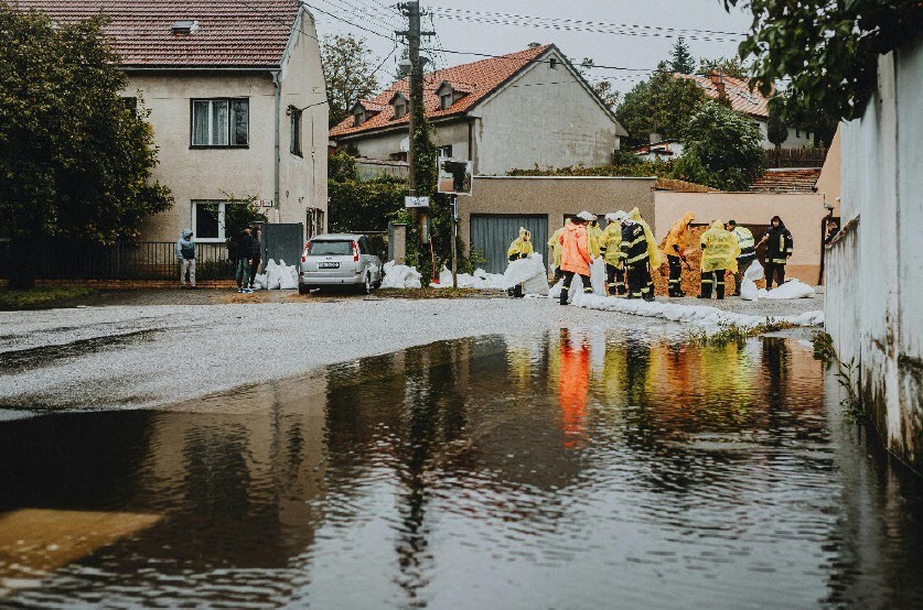 Workers laying out sand bags on a road to help contain flooding.