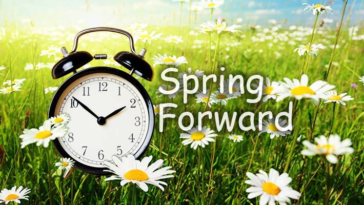 Spring forward. Clock in a field of flowers.