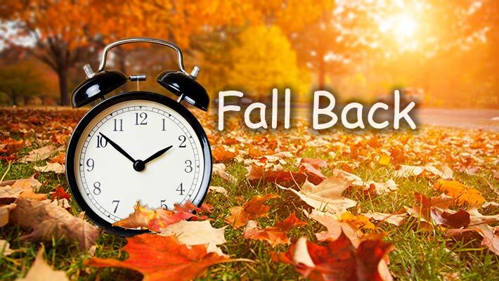 Fall Back. A clock surrounded by leaves.